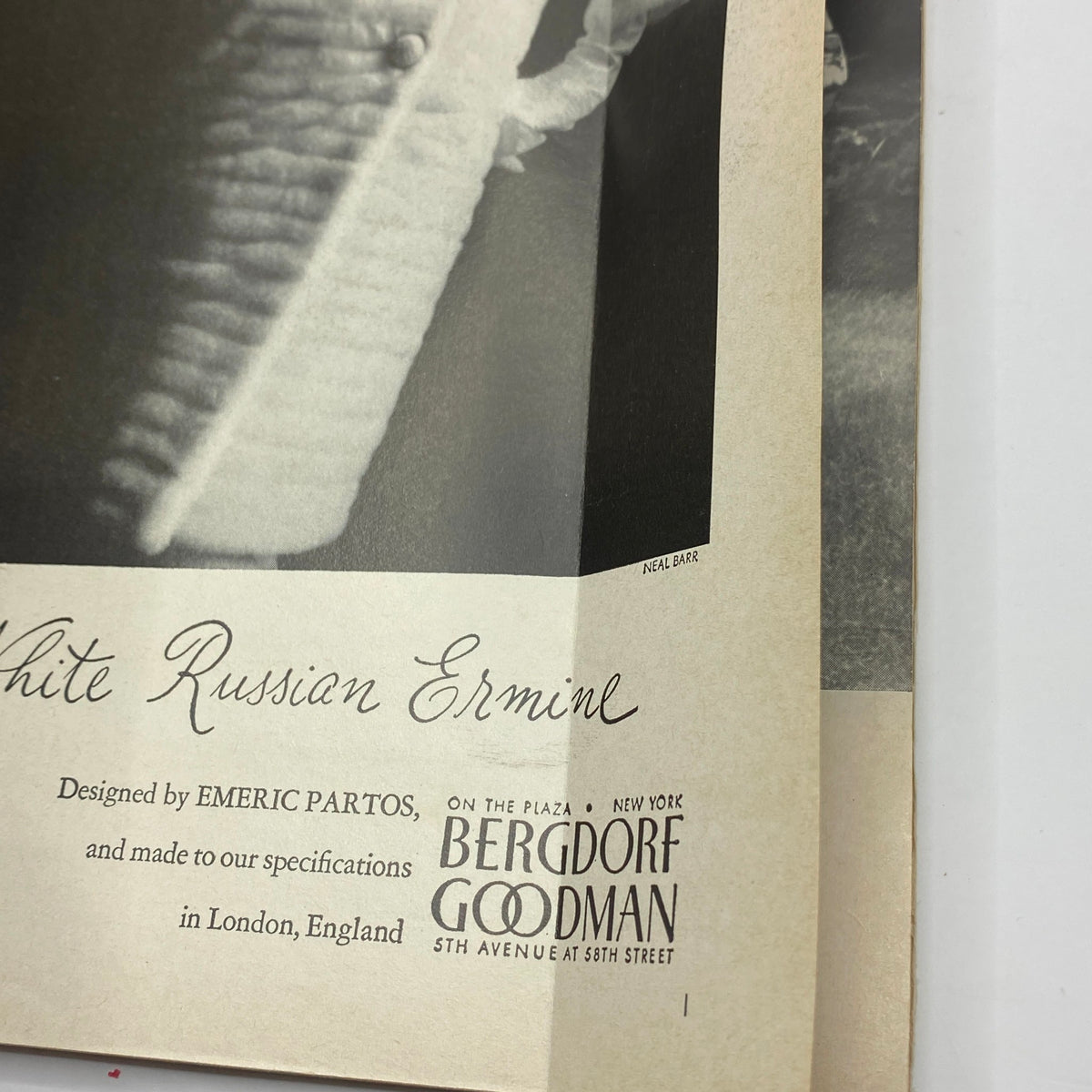 Detailed view of an advertisement from the VTG Vogue Magazine October 15, 1965, featuring the text 'White Russian Ermine' and the designer Emeric Partos.