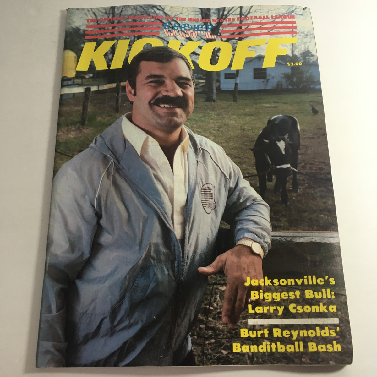Cover of VTG USFL Kickoff Official Magazine 1984 Vol. 2 #6 featuring Larry Csonka, showcasing a casual image of him smiling wearing a jacket with a bull in the background, promoting the excitement of vintage American football.