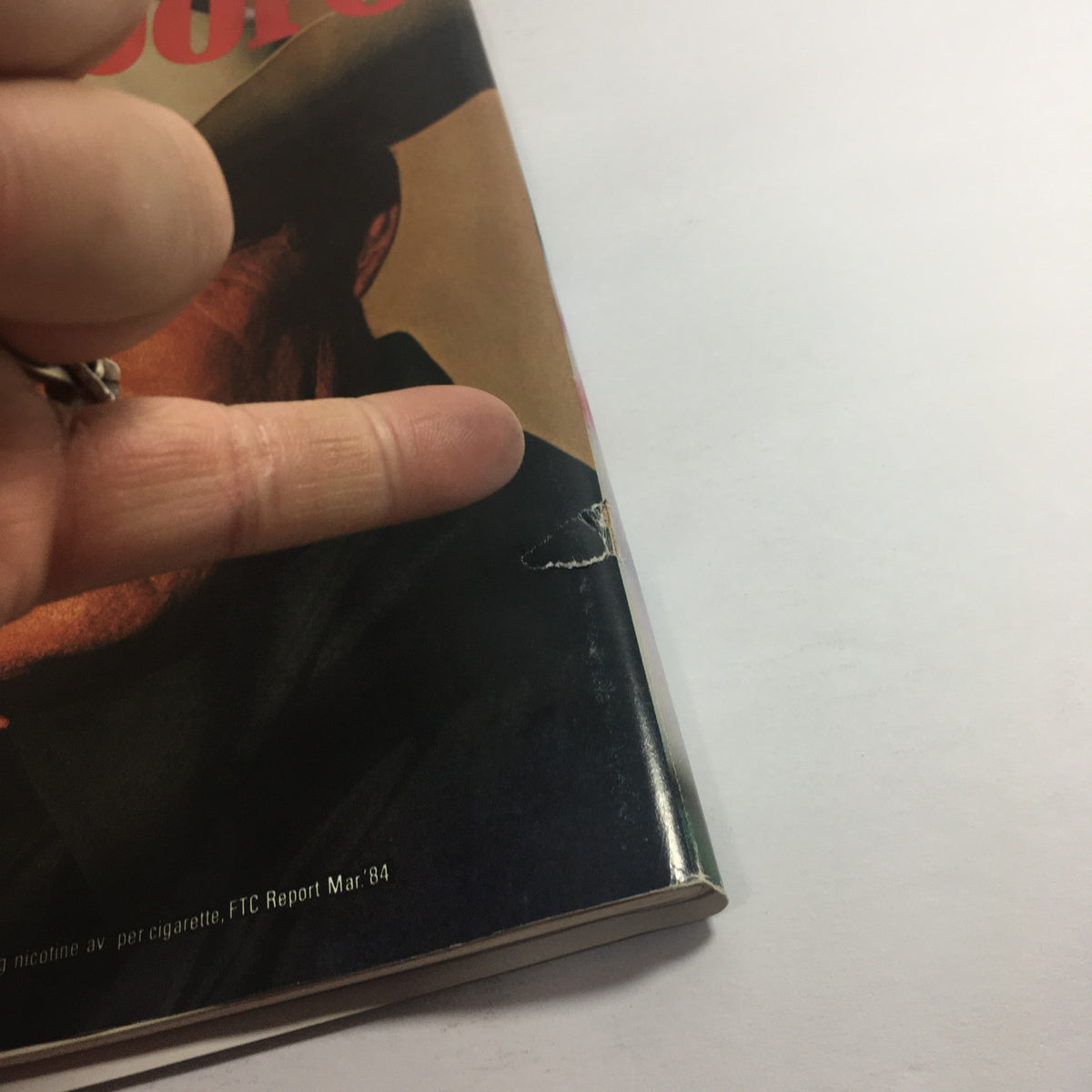 Detail shot of the vintage Marlboro magazine, focusing on the magazine’s corner showing wear and an advertisement warning about health risks.