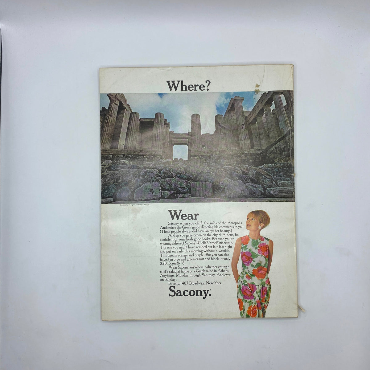 Back cover of VTG Vogue Magazine February 1 1966 featuring an advertisement with a woman modeling vibrant floral attire and a scenic backdrop.