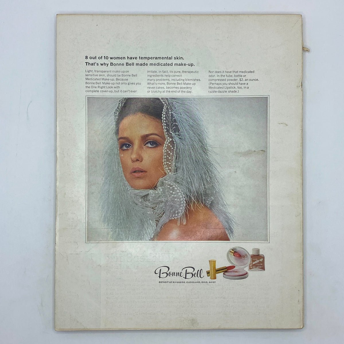 Advertisement in VTG Vogue Magazine October 1 1965 for Bonne Bell medicated make-up featuring a glamorous model with a pearl headdress and feathered accessories.
