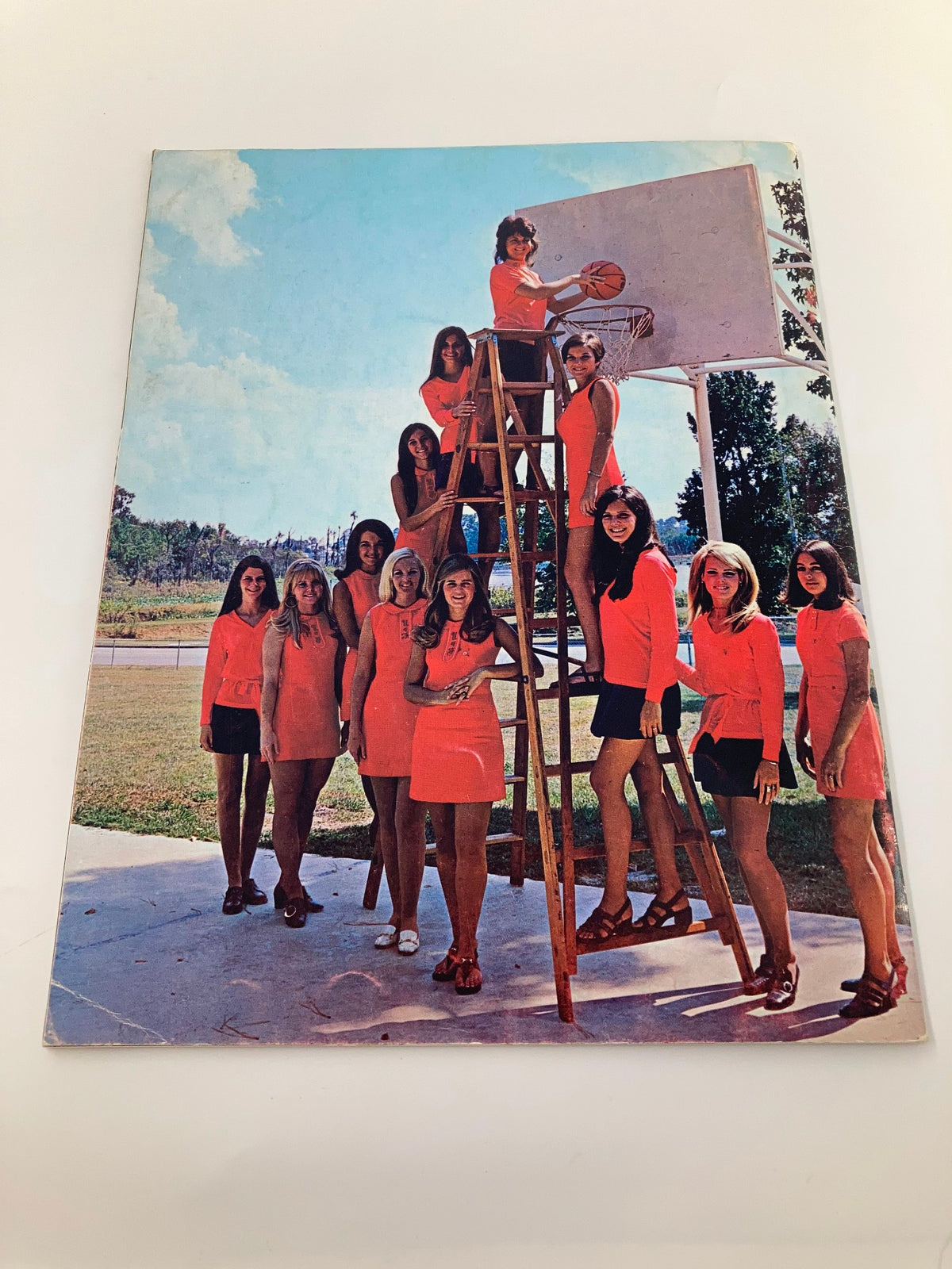 1970-1971 College University of Florida Gator Basketball Brochure featuring a group of women in vibrant orange attire posed by a basketball hoop, capturing a nostalgic moment in Gators history.