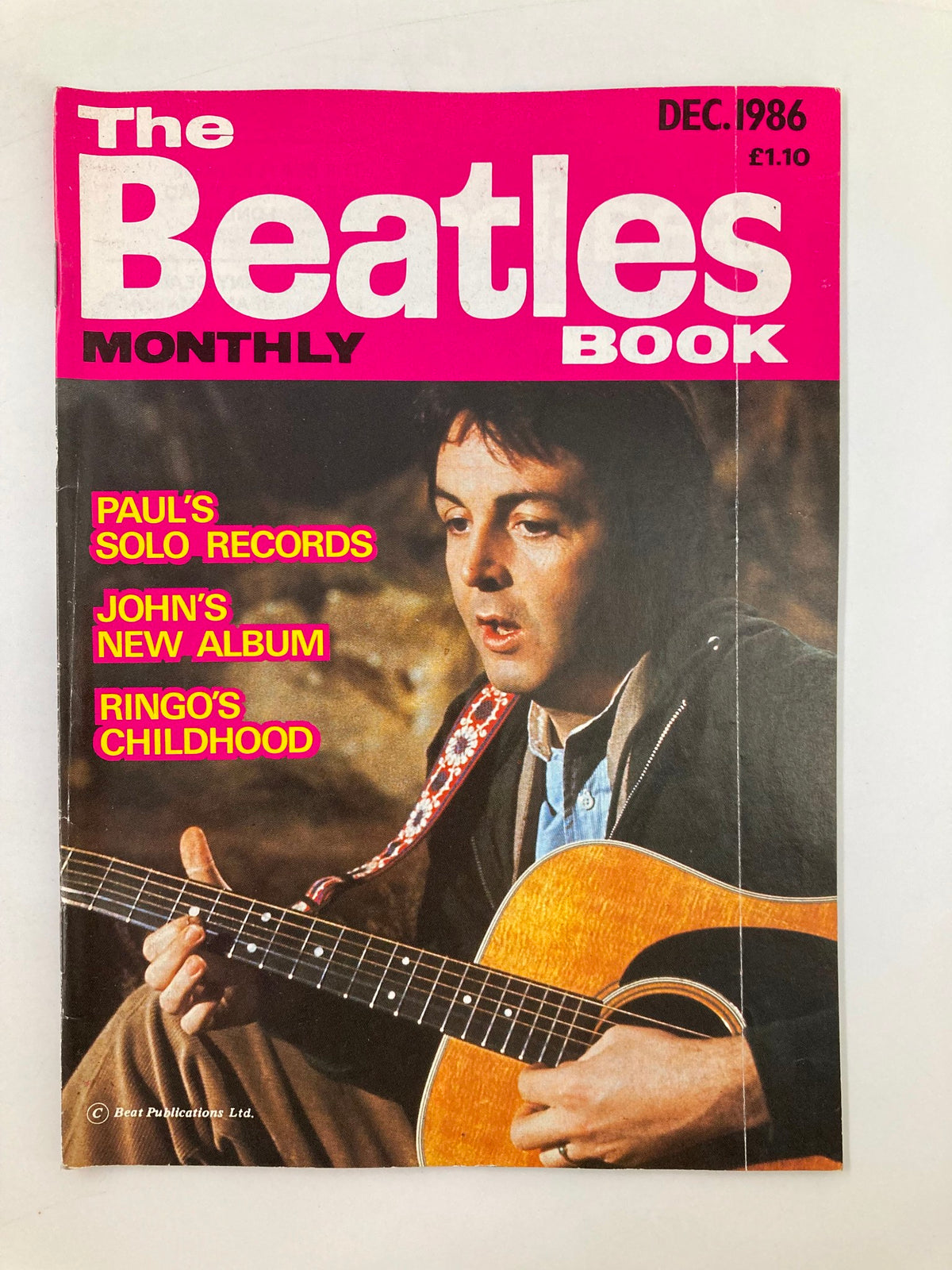 The Beatles Book Monthly Magazine December 1986 Issue #128 featuring Paul McCartney on the cover, showcasing him playing an acoustic guitar.