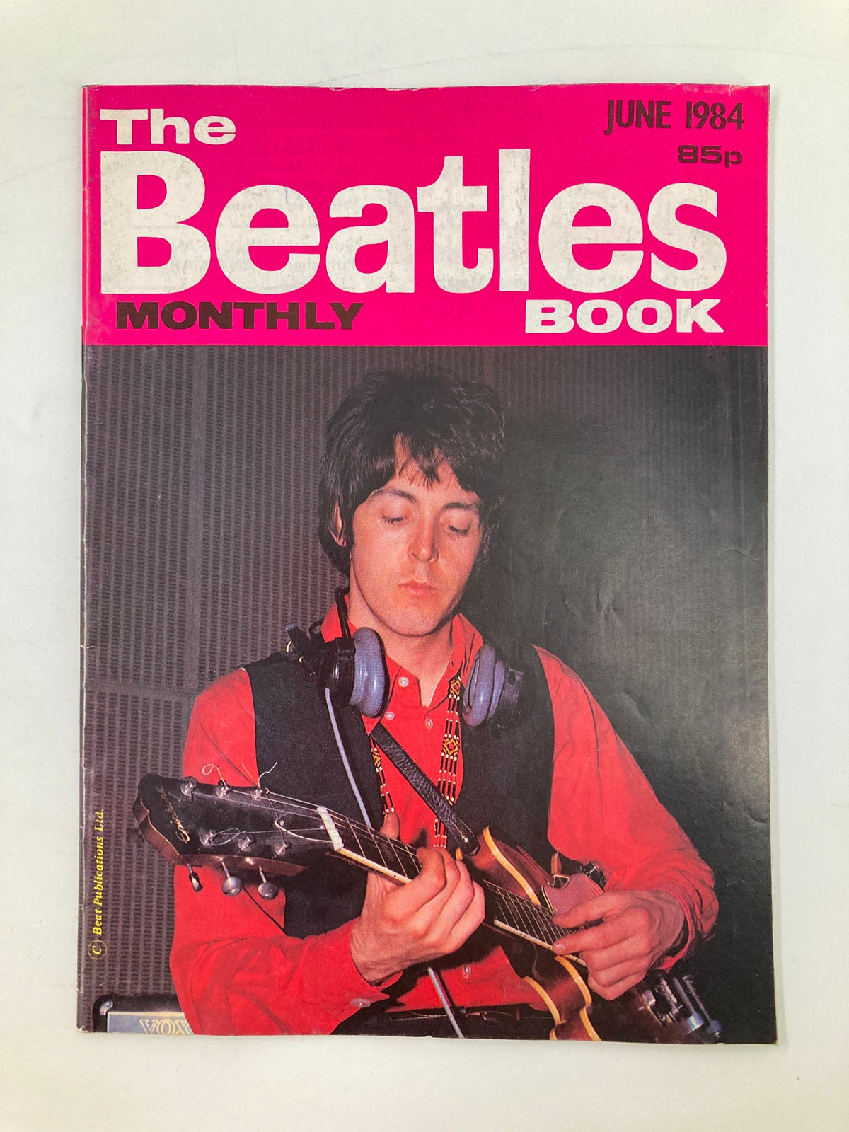 The Beatles Book Monthly Magazine June 1984, Issue #98 featuring a vintage cover image of a musician, likely Paul McCartney, playing guitar, showcasing the magazine's vibrant pink design and cultural significance.