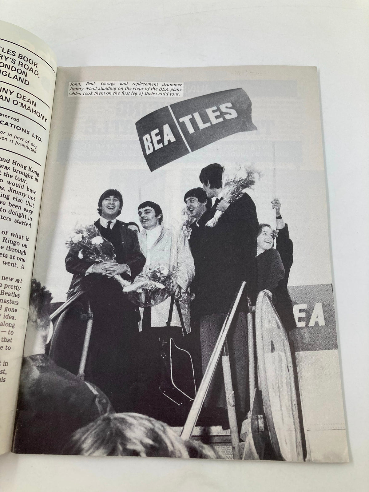 Black and white photo from The Beatles Book Monthly Magazine July 1984 #99 showing John, Paul, George, and Jimmy Nicol arriving at the airport with fans cheering.