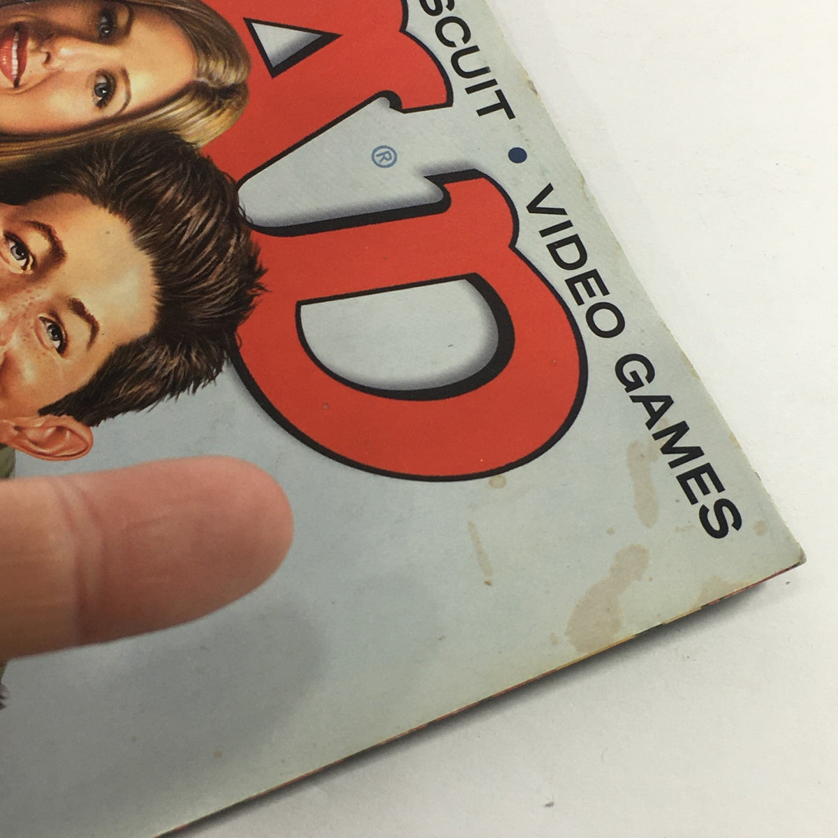 Close-up of the top corner of Mad Magazine November 2003 with a finger pointing at the magazine cover, showcasing some wear on the edges.