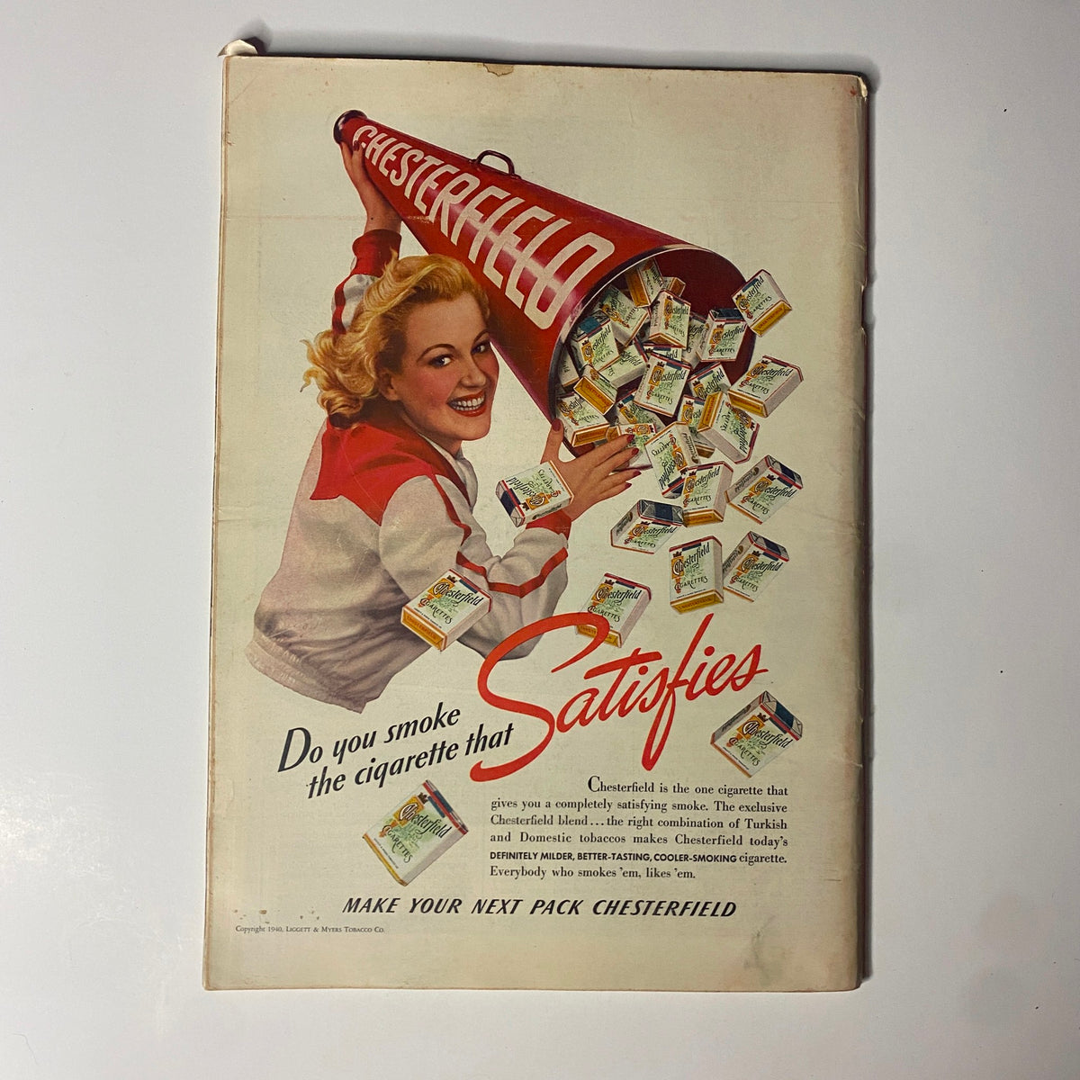 Vintage Chesterfield advertisement featuring a woman with a megaphone pouring out cigarette packs, promoting the slogan 'Do you smoke the cigarette that Satisfies'.