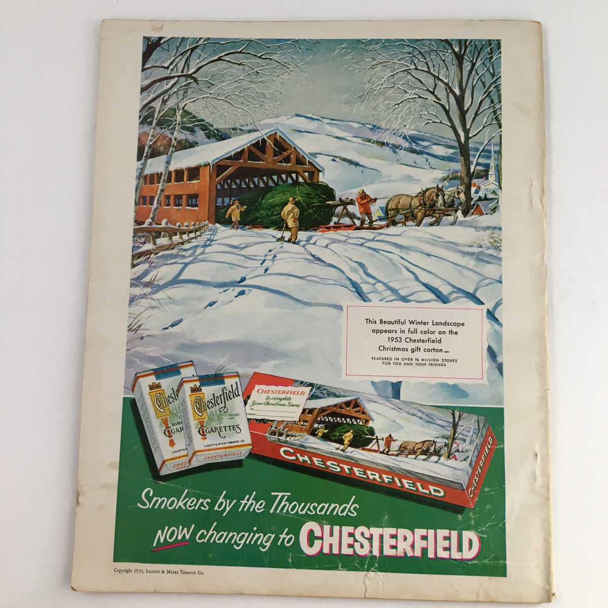 Back cover of the Photoplay Magazine December 1953 displaying a colorful winter landscape advertisement for Chesterfield cigarettes, featuring people in a snowy setting and a horse-drawn sled.