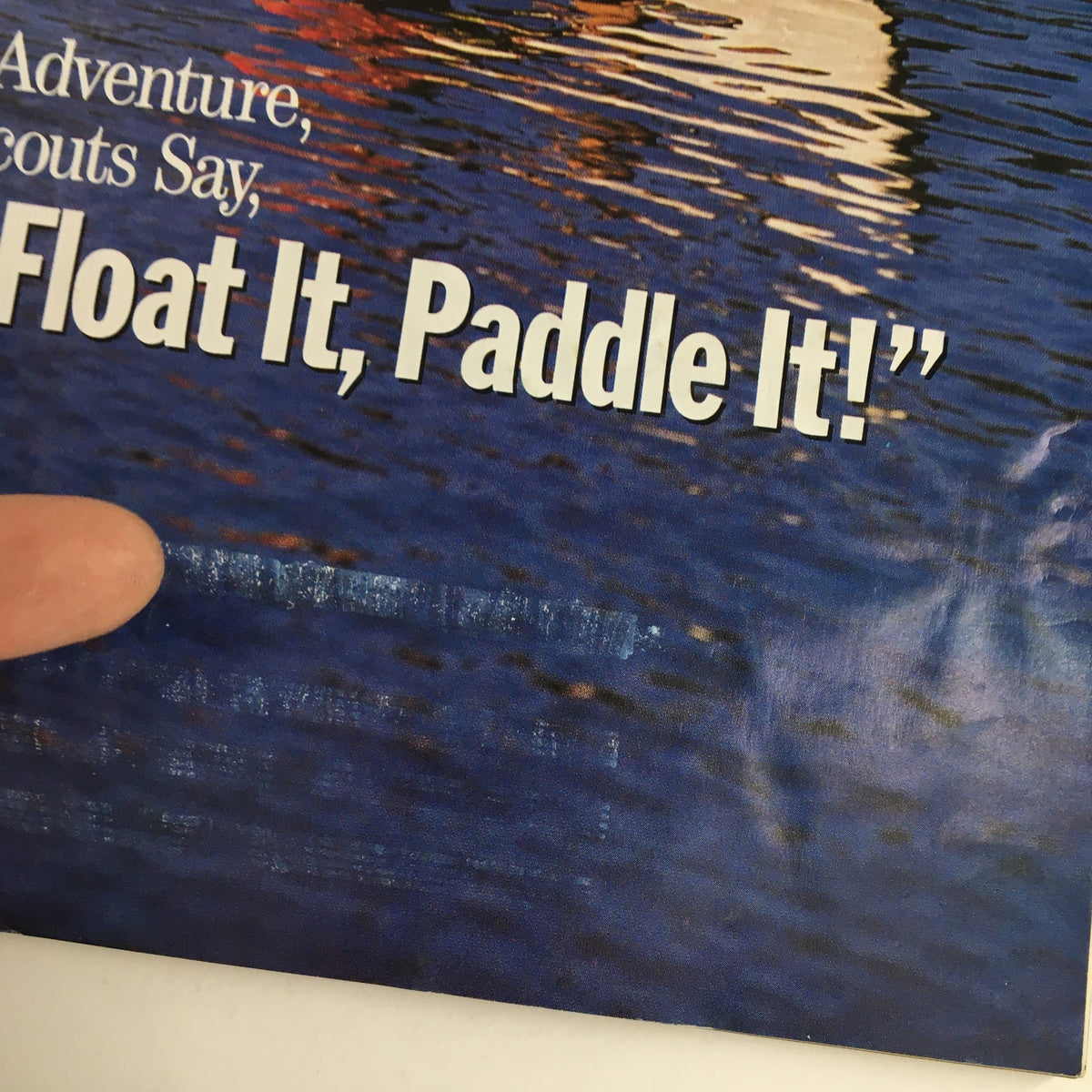 Close-up of Boys' Life Magazine cover from May 1991 highlighting the phrase 'Build It, Float It, Paddle It!' against a reflective water backdrop, with a finger pointing to the text.