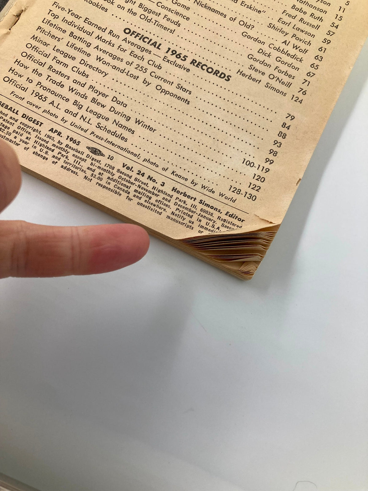 Detail of the inside pages of VTG Baseball Digest April 1965 showing the official records for 1965, with a finger pointing at specific entries and vintage-styled text.
