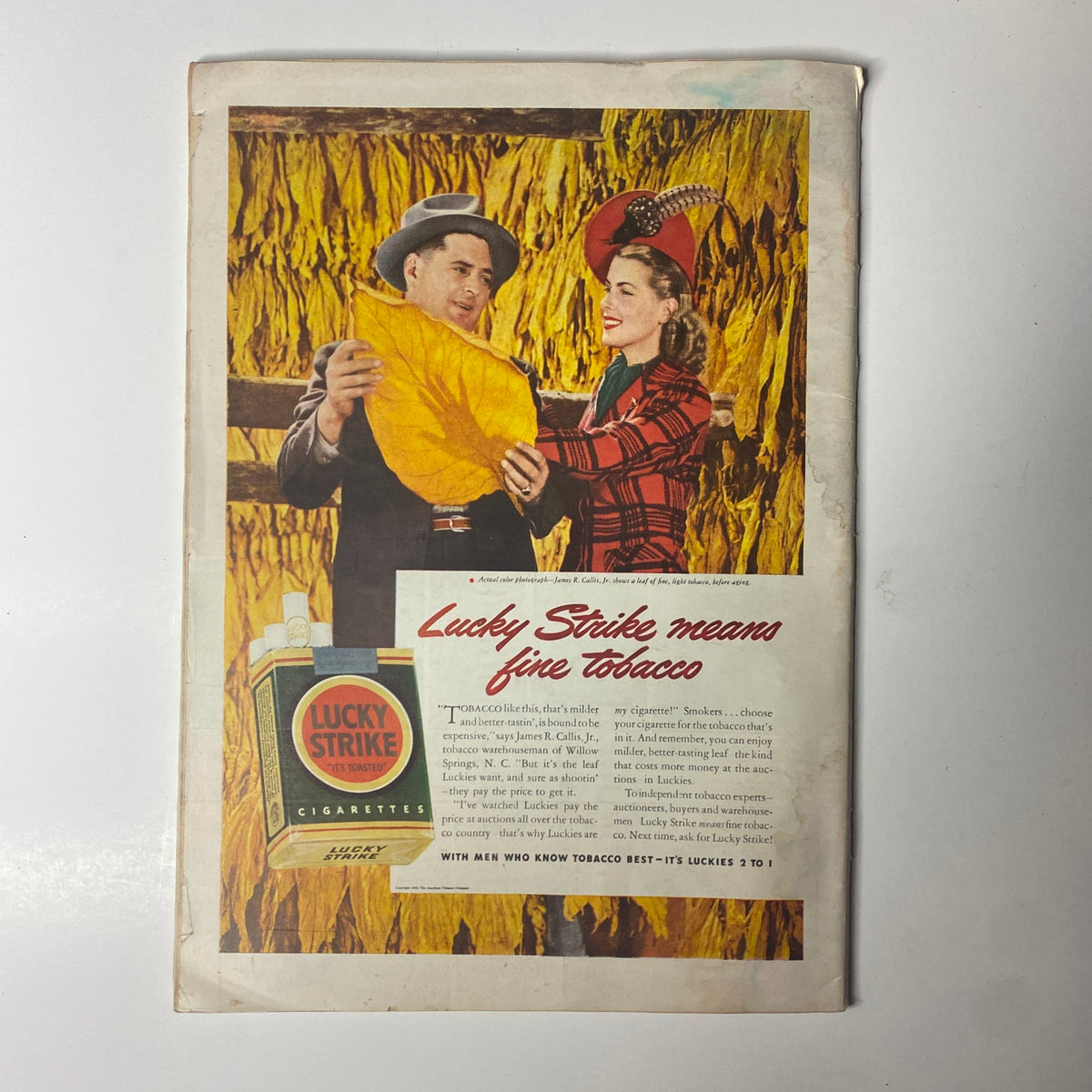 Back cover advertisement for Lucky Strike cigarettes from a vintage magazine, showcasing a couple smiling while holding a large tobacco leaf, emphasizing quality tobacco.