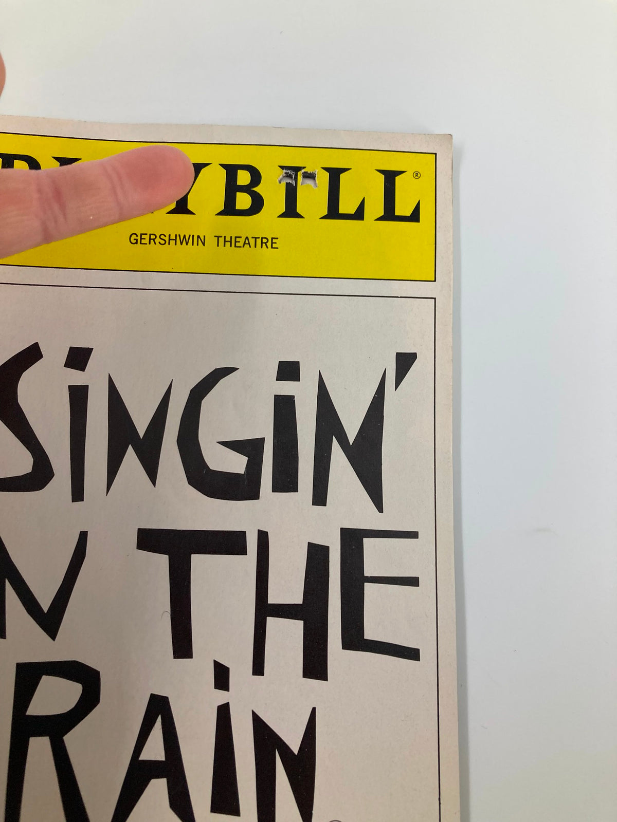 Close-up of the top section of the 1986 Playbill for 'Singin' In The Rain' at the Gershwin Theatre, featuring a visible staple and yellow header.