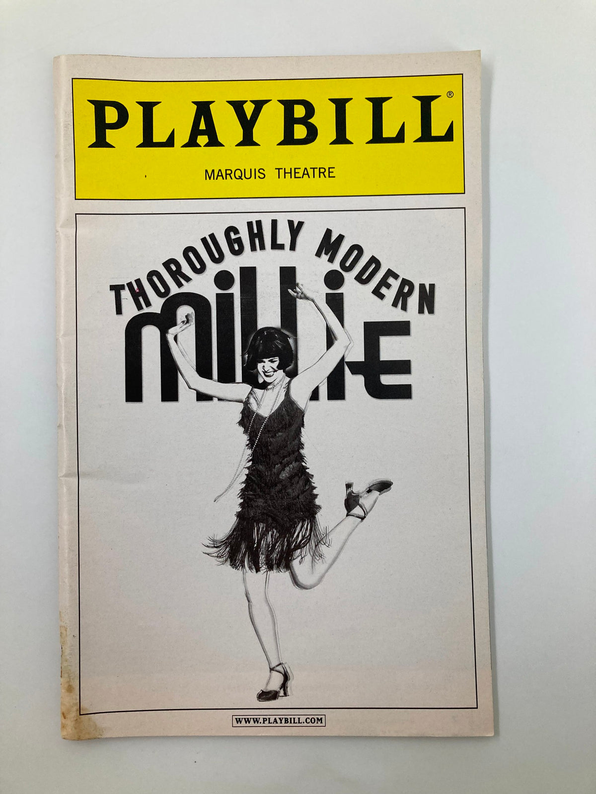 2002 Playbill for Thoroughly Modern Millie from the Marquis Theatre showing a vintage design with a dancer wearing a flapper dress.