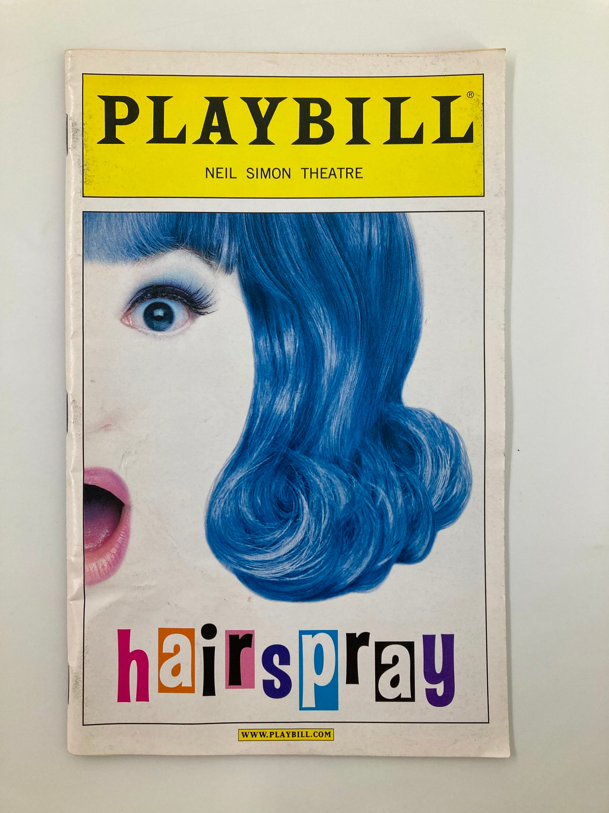 2004 Playbill for Hairspray at Neil Simon Theatre featuring a vibrant cover with a woman's face and a blue hairdo, showcasing the musical's title in colorful letters.