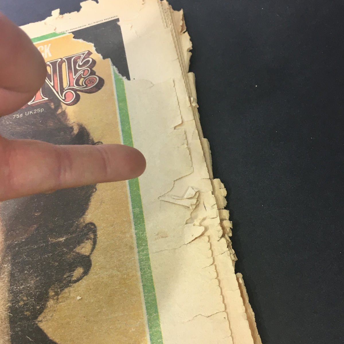 Close-up view of the damaged edge of the VTG Rolling Stone Magazine May 9, 1974 highlighting its vintage condition.