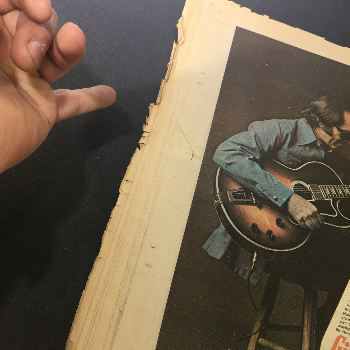 Side view of the Rolling Stone Magazine May 9, 1974, highlighting frayed edges and a hand pointing towards the cover photo of an artist, emphasizing its vintage appeal.