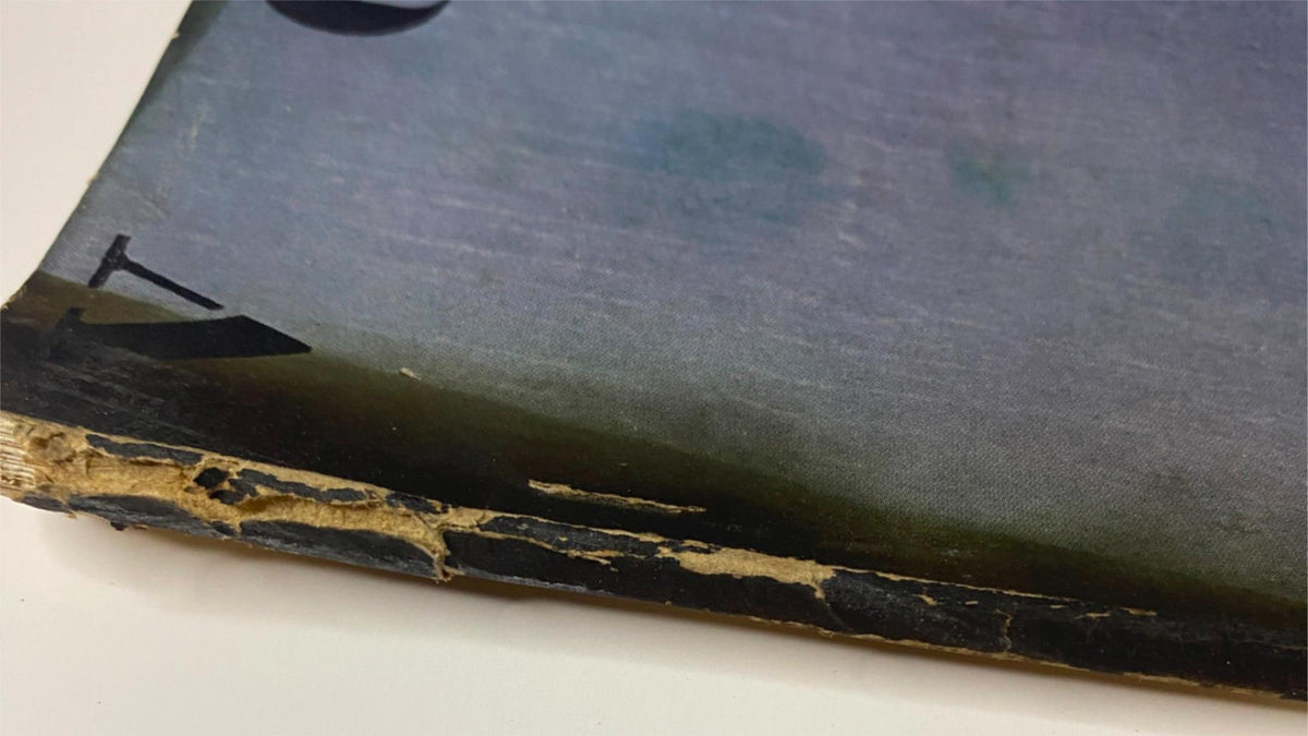Close-up of the spine of Vogue Magazine, July 1, 1938, showing wear and tear, along with the ocean background from the cover illustration 'Hot Weather Holidays' by Georges Lepape.