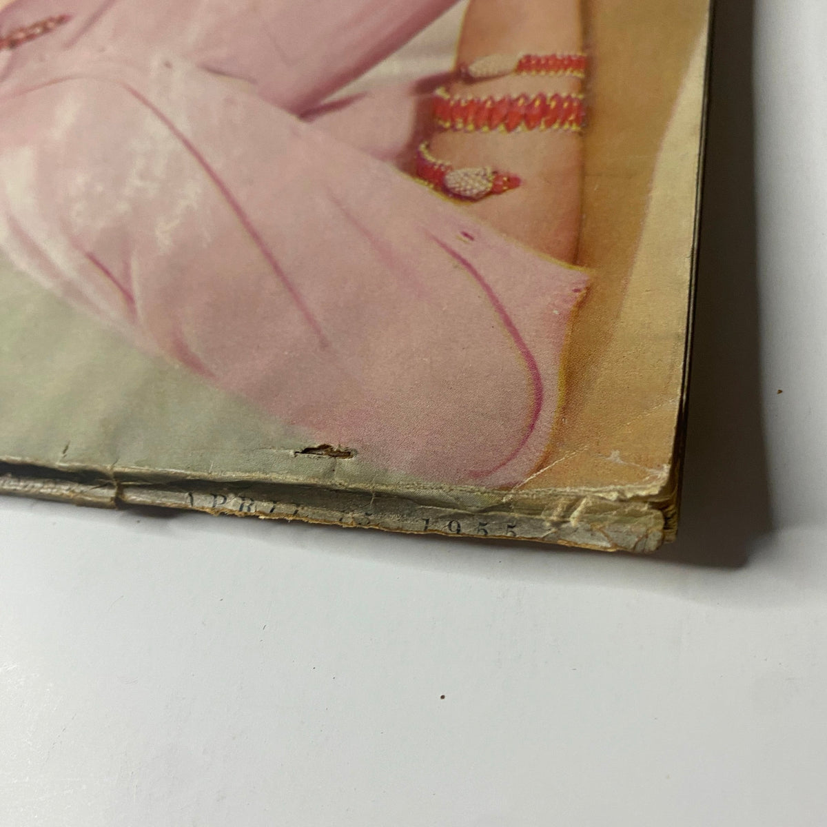 Close-up detail of Vogue Magazine April 15, 1955, showing a slight crease and wear near the bottom, reflecting the authenticity of this vintage publication.