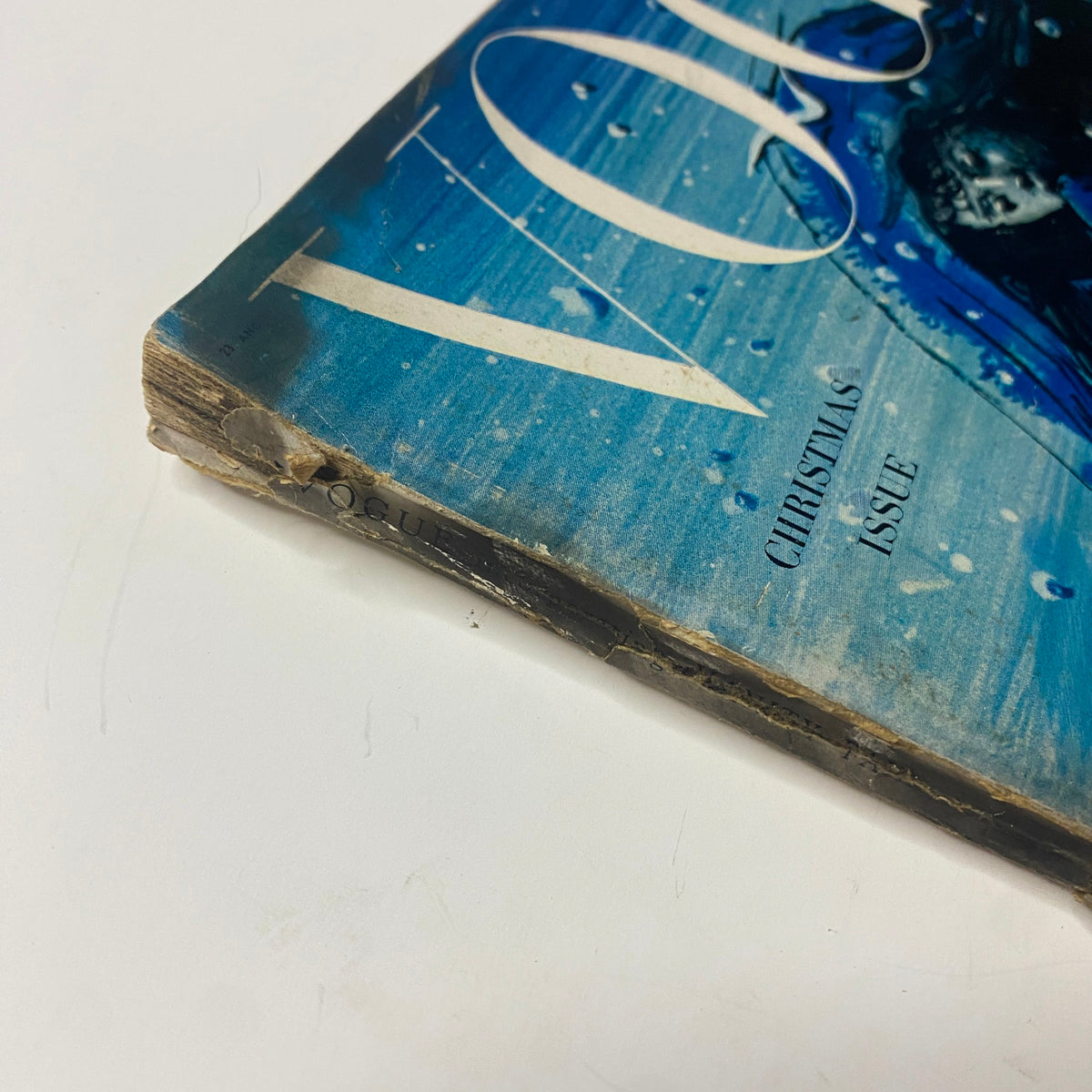 Close-up of the spine of the Vogue Magazine December 1948 Christmas Issue, showing signs of age and wear, featuring the title and date prominently.