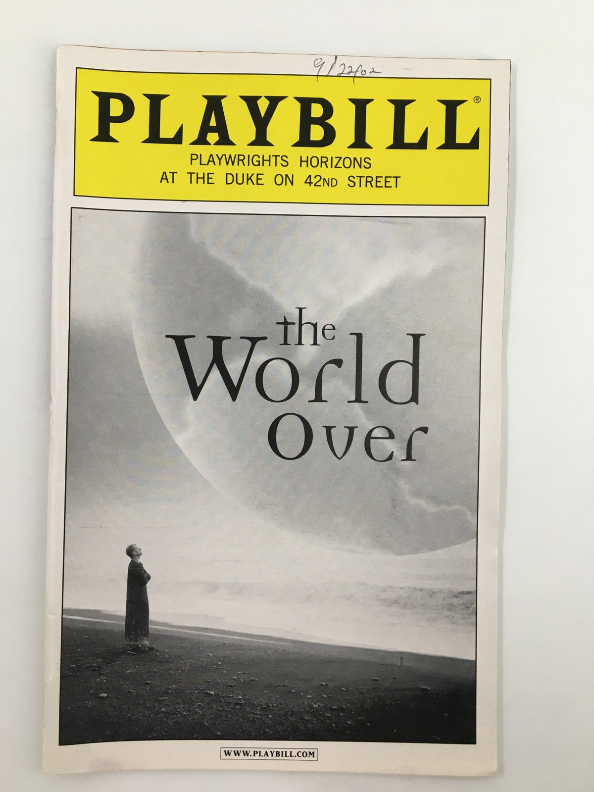 Cover of the 2002 Playbill for The World Over by Keith Bunin, featuring a serene image of a woman on the shore with the title prominently displayed.