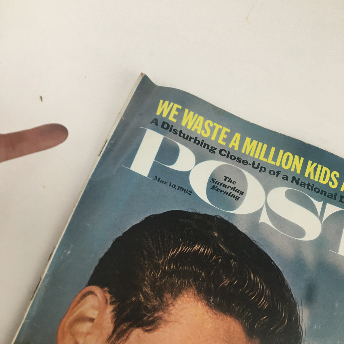 A close-up view of the cover of The Saturday Evening Post March 10, 1962, showing the title 'We Waste A Million Kids A Year' and highlighting the image of a young man deep in thought.