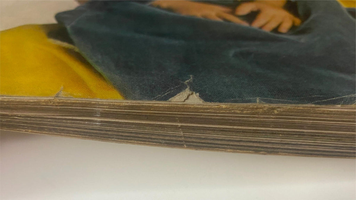 Close-up image of the spine of Vogue Magazine December 1962, showcasing wear and tear over time, with visible frays along the edges.
