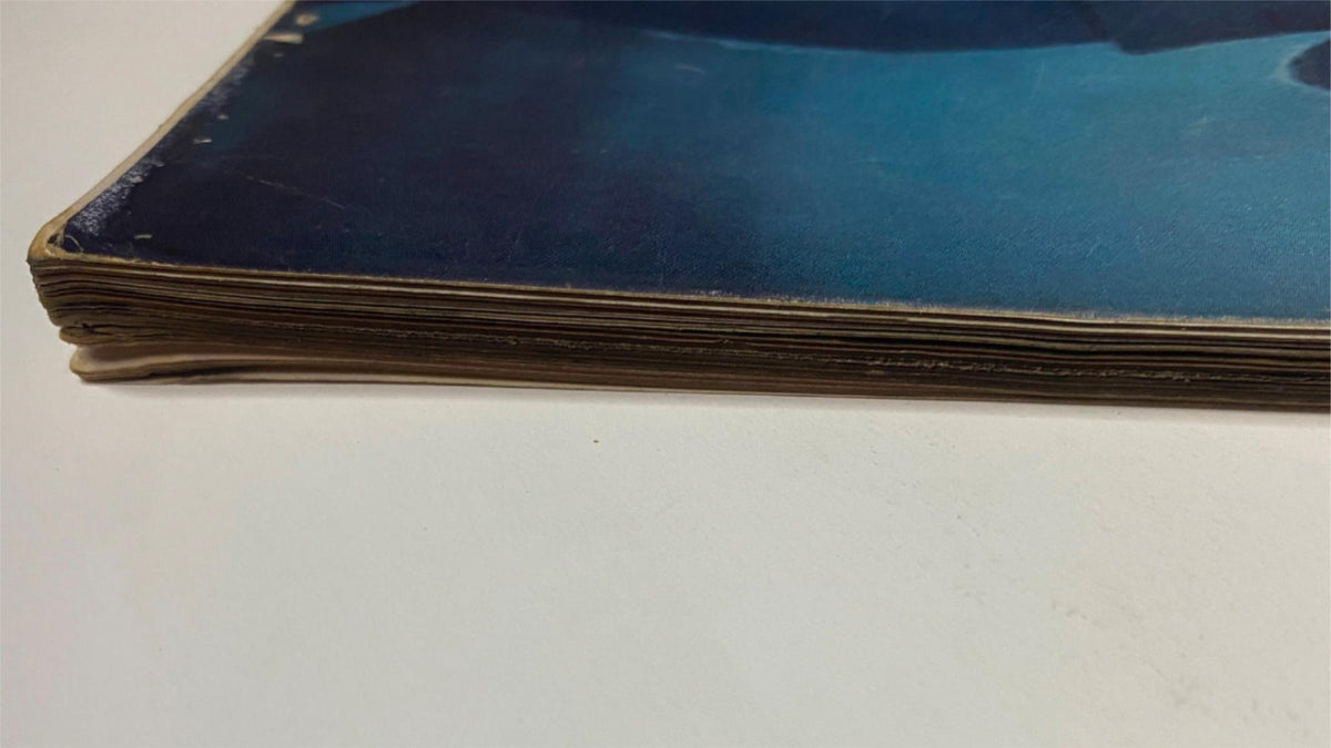 Side view of the spine of Vogue Magazine December 1957 Gyongyi Armstrong Cover by Karen Radkai, highlighting its well-preserved condition despite visible age.