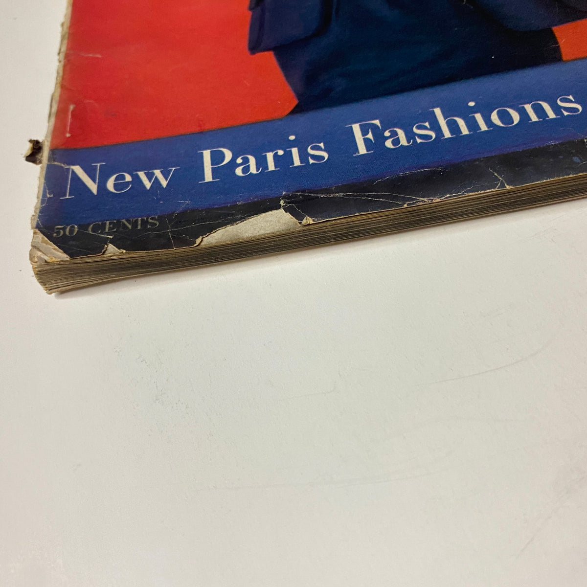Corner detail of Vogue Magazine March 15, 1957, revealing wear and tear, with a caption about 'New Paris Fashions' highlighting mid-century couture trends.