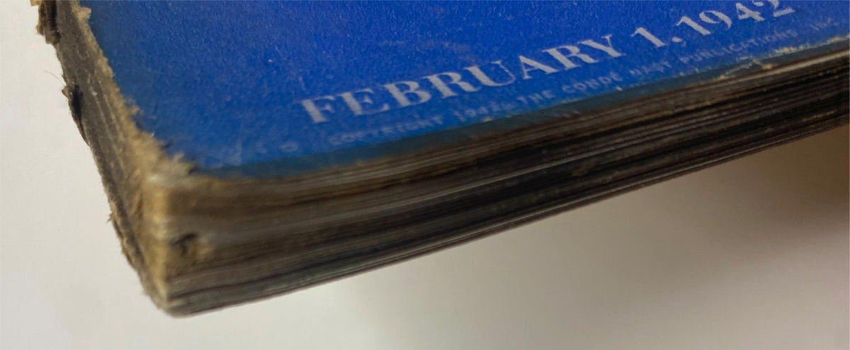 Close-up view of the spine of Vogue Magazine, February 1, 1942, showcasing its vintage wear and condition details. The magazine is themed 'Life in Wartime: Women in the Morale Corps', highlighting its historical significance.