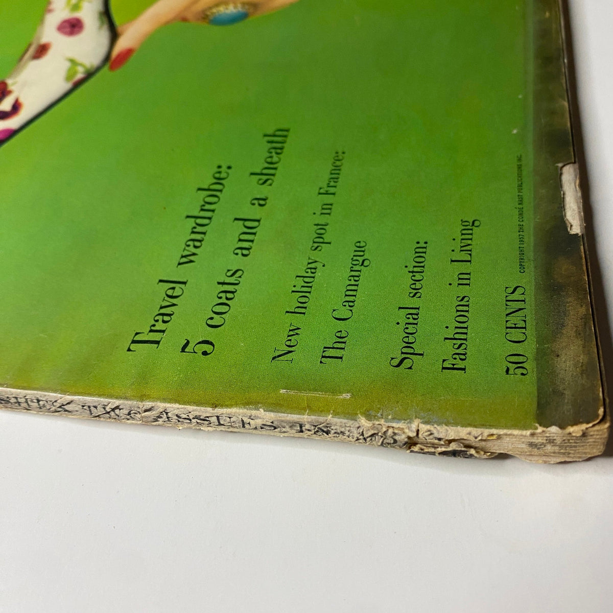 Cover detail of Vogue Magazine April 15, 1957 featuring the article 'Travel wardrobe: 5 coats and a sheath' by Richard Rutledge. Vintage publication with wear and archival artifacts.
