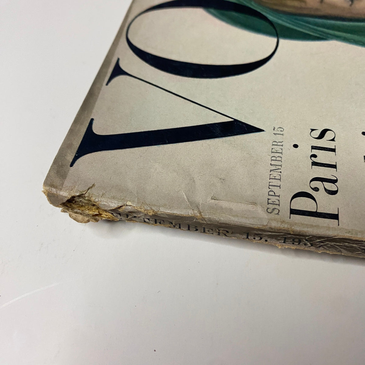 Detail of the damaged spine of Vogue Magazine September 15, 1957 featuring cover with Mary Jane Russell photographed by John Rawlings, showcasing vintage wear.