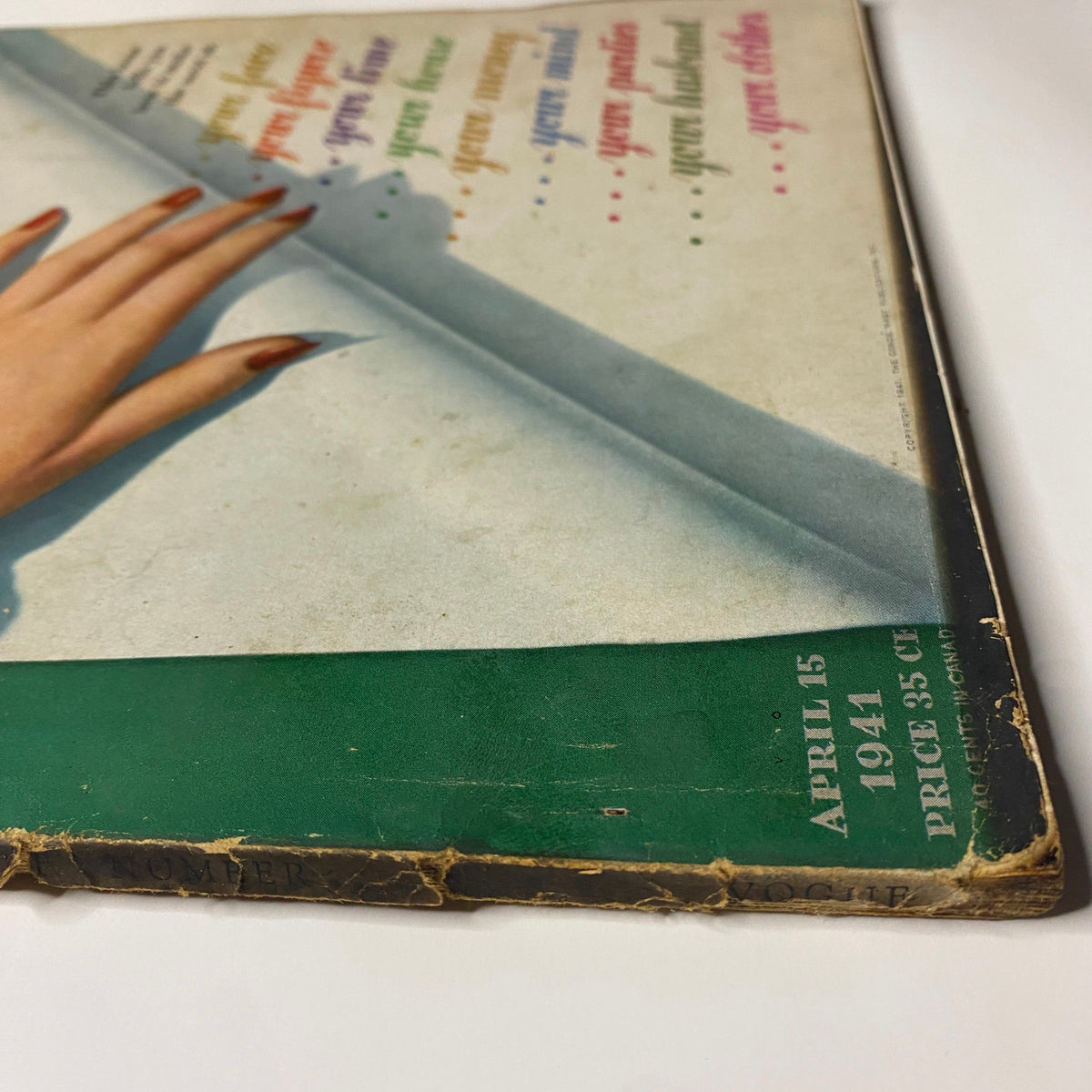 Bottom view of Vogue Magazine April 15, 1941 showing wear and tear, with a focus on the title and price, reflecting the magazine's classic vintage appeal.