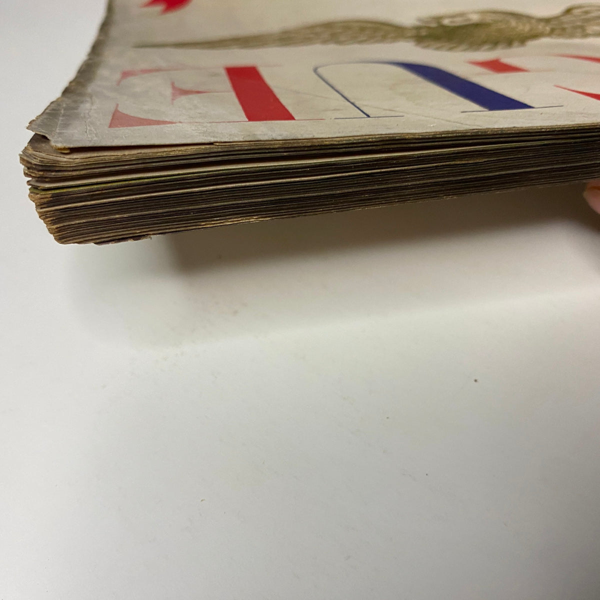 Close-up of the frayed spine of Vogue Magazine February 1, 1947, showcasing the magazine's historical preservation and vintage condition.