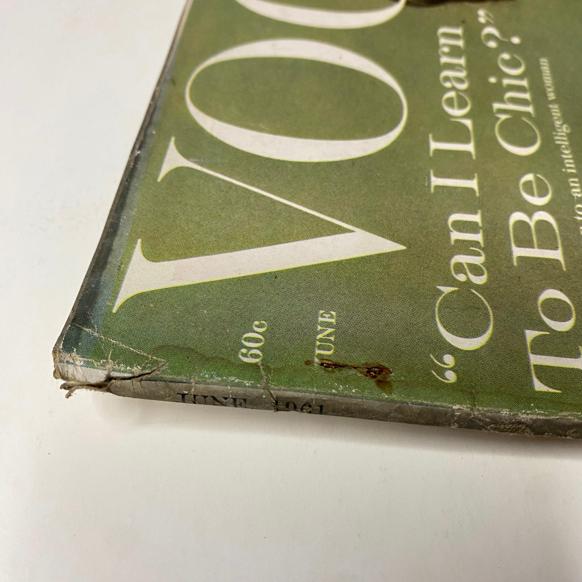 Close-up view of the worn corner of Vogue Magazine June 1961 featuring Dorothy McGowan on the cover, showcasing age-related damage and vintage characteristics.