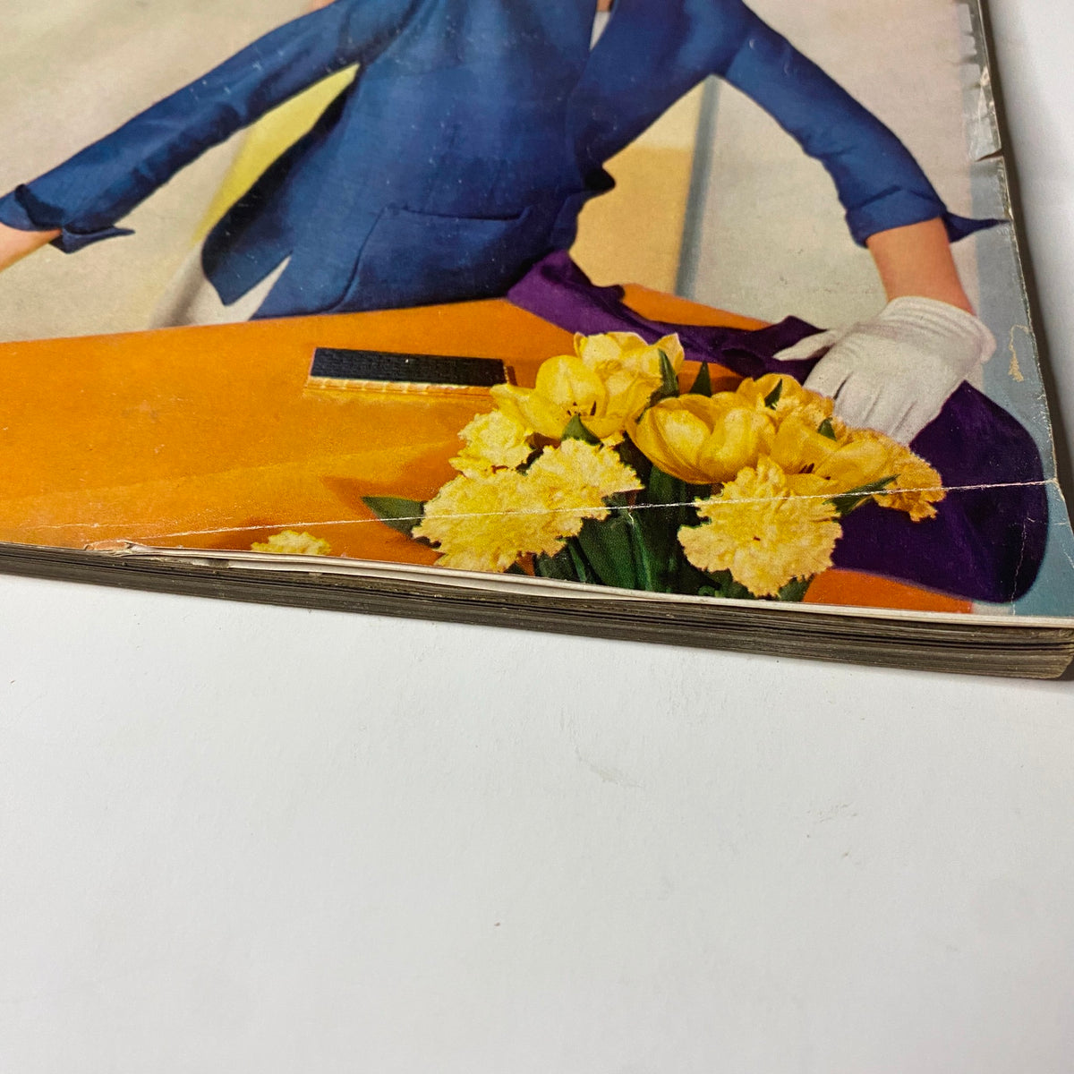 Close-up of the edge of Vogue Magazine May 1, 1955 Summer Fashion Textbook, showing vintage wear and storage conditions.