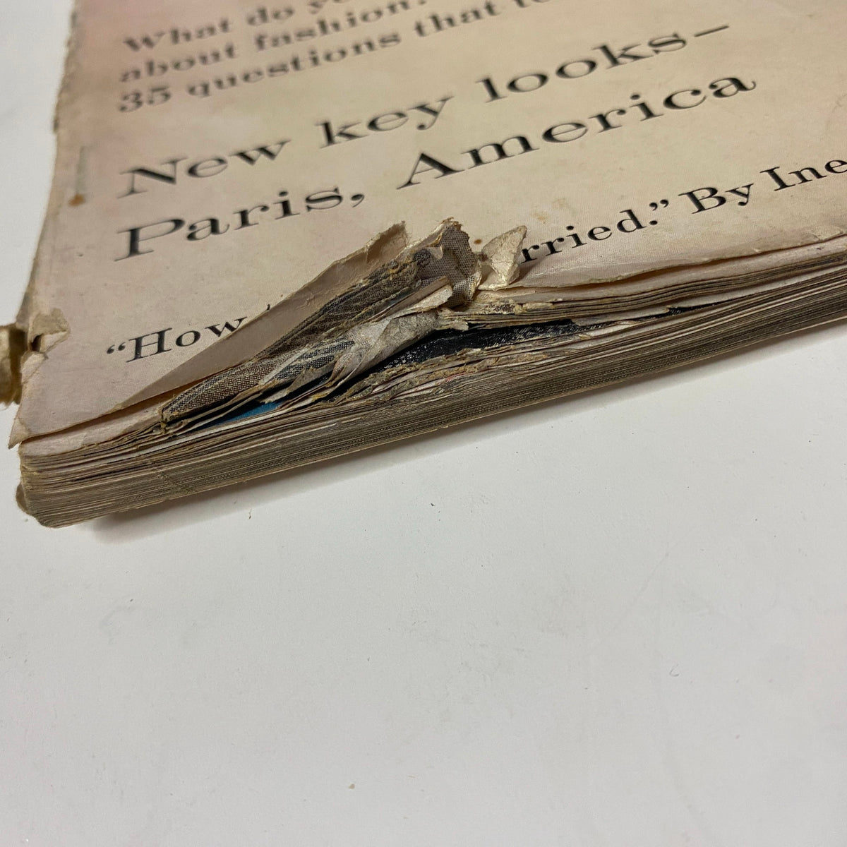 Close-up of the damaged spine of Vogue Magazine March 1, 1959 featuring Isabella Albonico, showcasing significant wear and tear, highlighting the vintage nature of the publication.