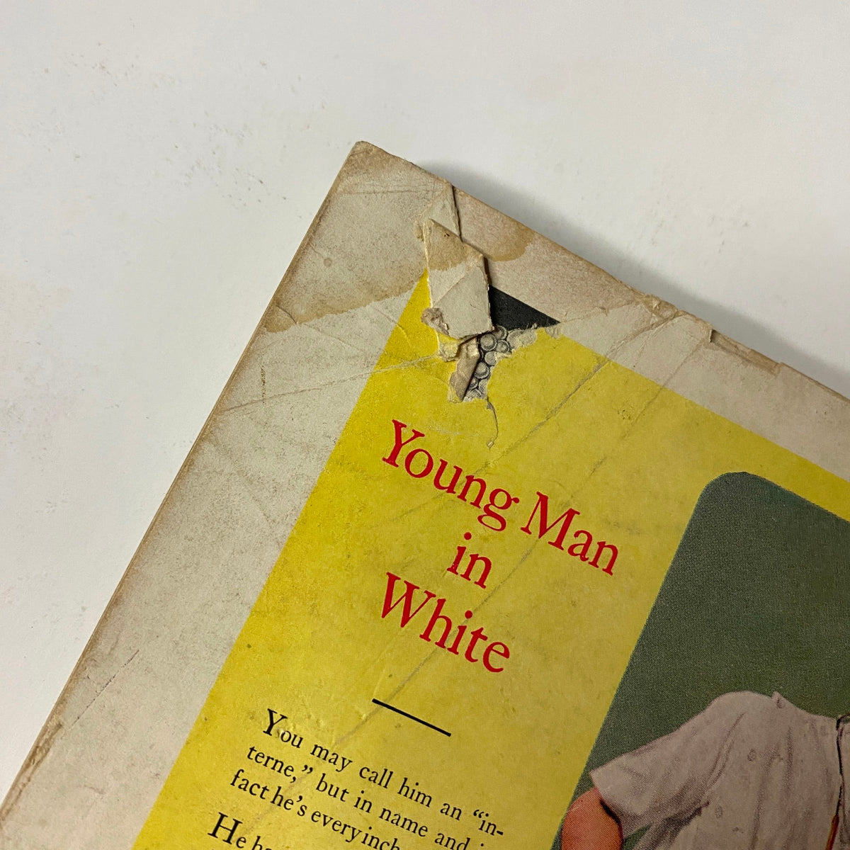 Close-up of a damaged cover of Vogue Magazine November 1, 1946, featuring the text 'Young Man in White' with visible wear and tear.