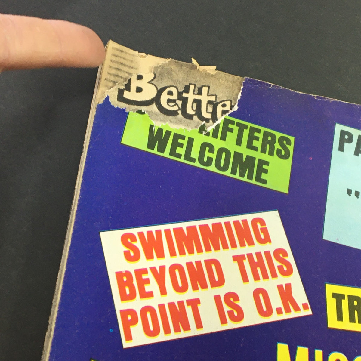 Close-up view of the cover edge of Wacko Magazine October 1981 Issue #3, showcasing a torn section with text elements including 'Better,' 'Lifters Welcome,' and 'Swimming Beyond This Point is O.K.' highlighting the magazine's eclectic design.