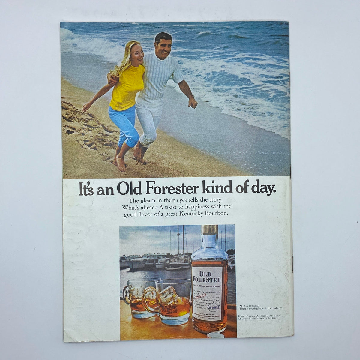 Back cover of an Old Forester advertisement featuring a couple joyfully walking along the beach, promoting Old Forester bourbon, with an image of the bottle and glasses.