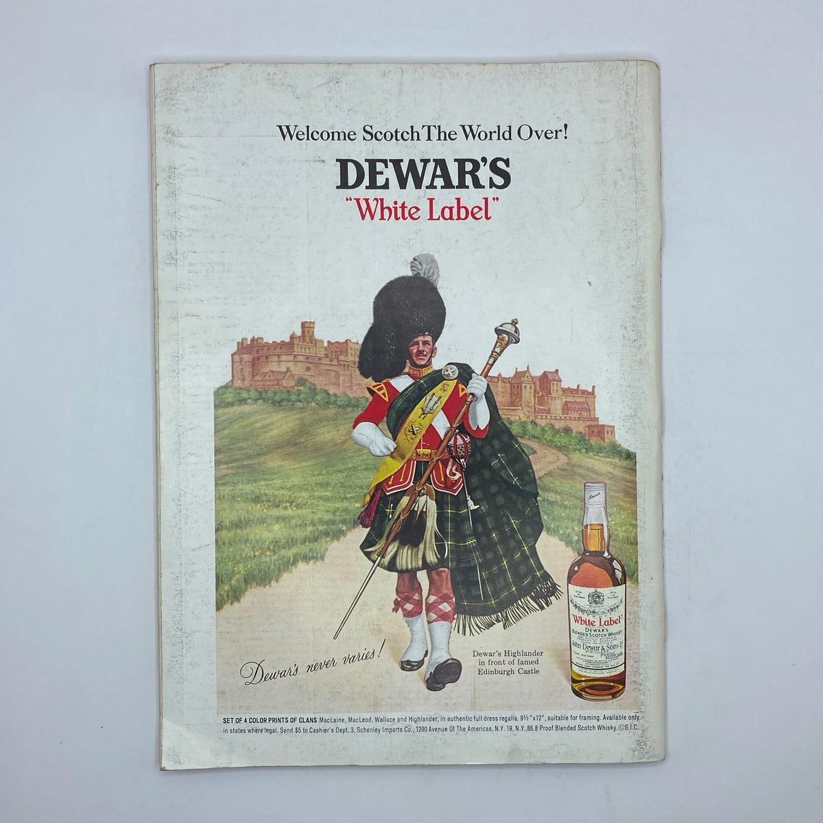 Back cover ad for Dewar's White Label whiskey, featuring a Scottish Highlander in traditional dress in front of Edinburgh Castle.