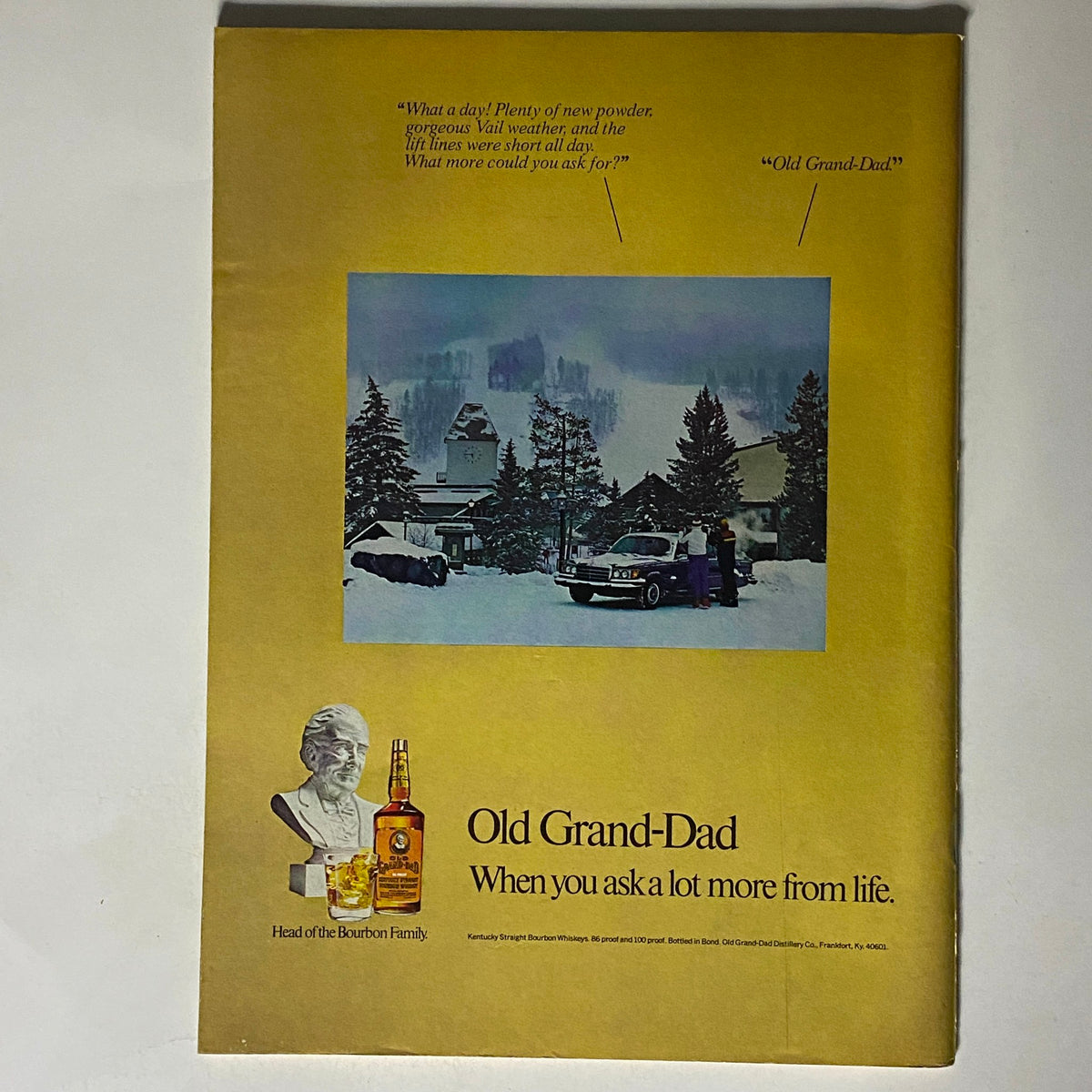 Back cover advertisement for Old Grand-Dad bourbon featuring winter scenery and promotional text from The New Yorker Complete Magazine February 14, 1977.