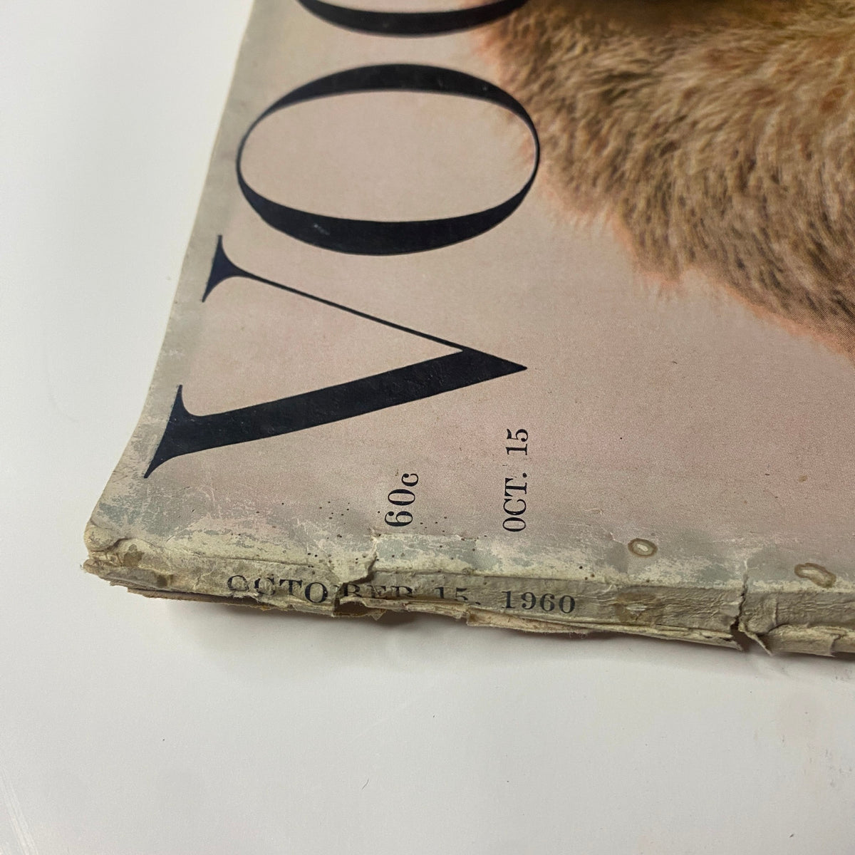 Close-up of the October 15, 1960 issue of Vogue Magazine featuring a weathered cover with visible wear, including torn edges and creases, highlighting the historicity of the publication by Tom Palumbo featuring Angela Howard.