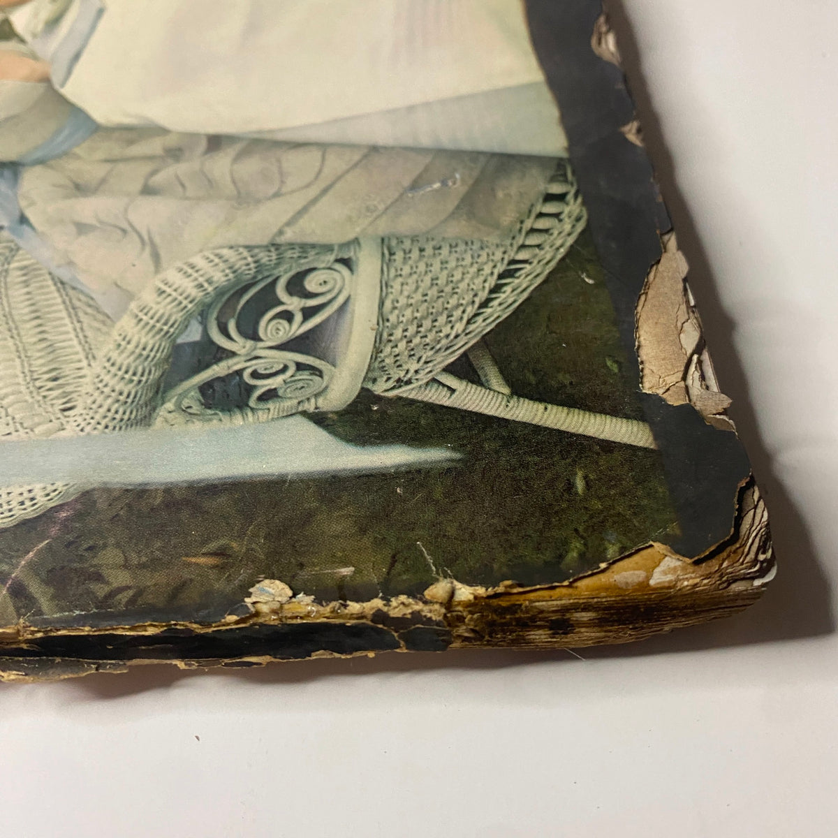Detailed view of the lower corner of the April 1, 1948 Vogue Magazine cover, showcasing visible damage and fraying, yet highlighting the Summer Fashion Preview theme with a woman enjoying a tranquil outdoor scene.