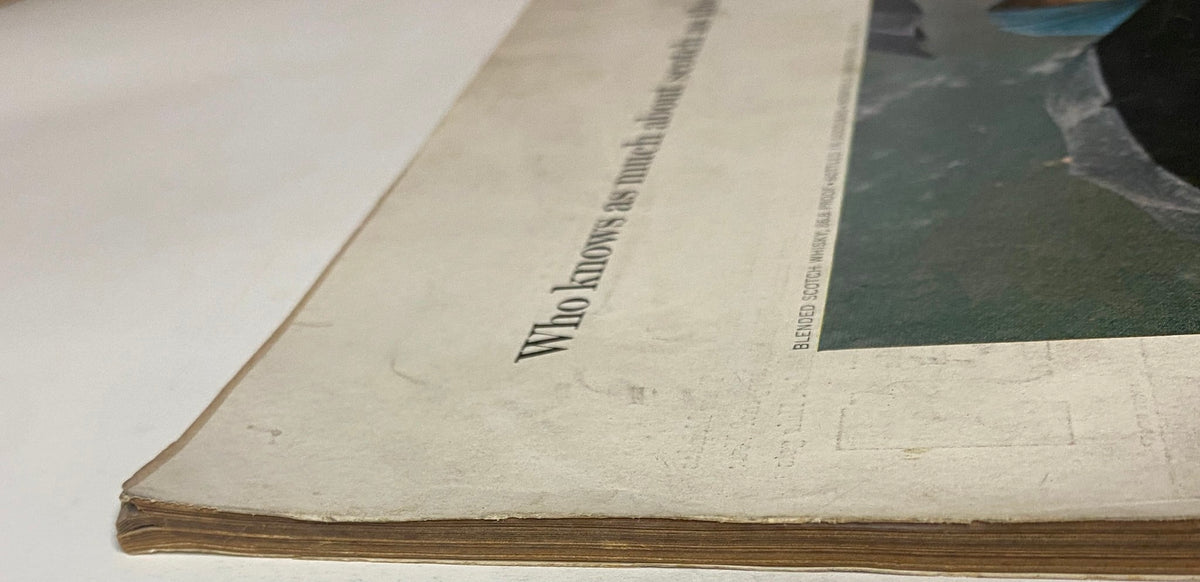 Detailed view of the edge of a page from Vogue Magazine July 1964 with a notable tagline discussing scotch, showcasing its vintage condition.