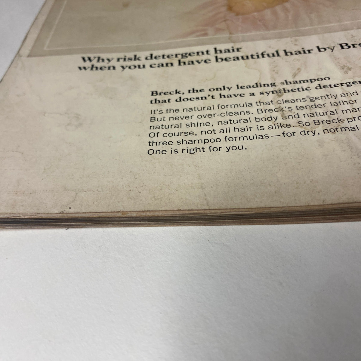Close-up of a vintage magazine page featuring an advertisement for Breck shampoo, emphasizing the benefits of beautiful hair without synthetic detergents. The ad showcases a soft focus corner revealing wear and age, typical of mid-20th century publications. Title: Vogue Magazine August 15, 1965 Veruschka Cover by Irving Penn.