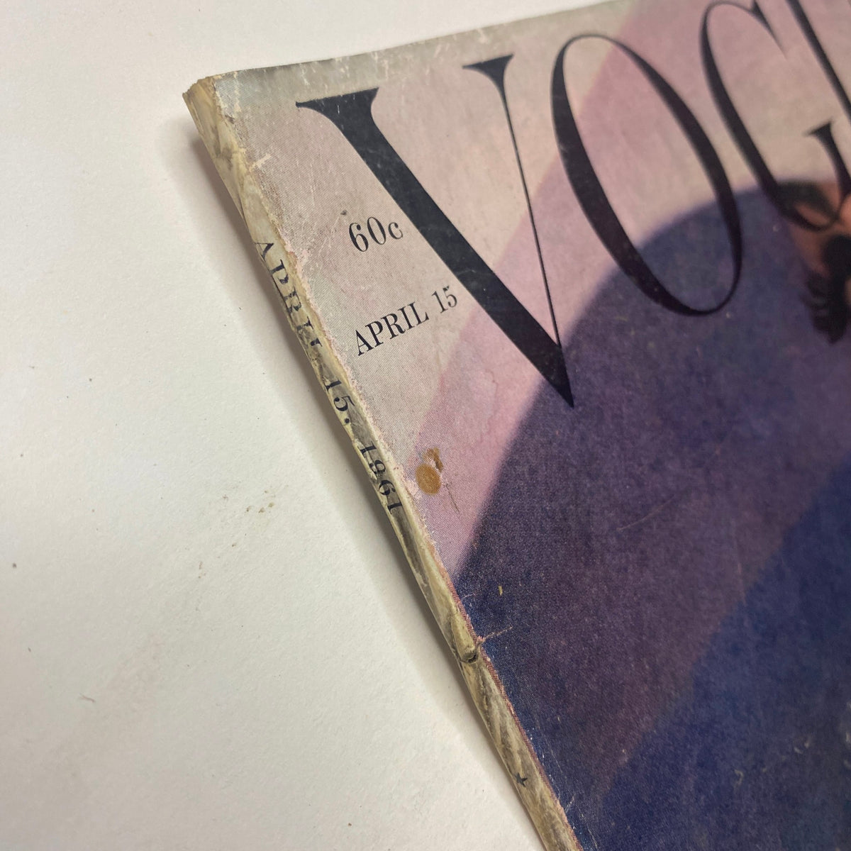 Close-up view of the spine of Vogue Magazine April 15, 1961, featuring discoloration and wear, highlighting its vintage condition.