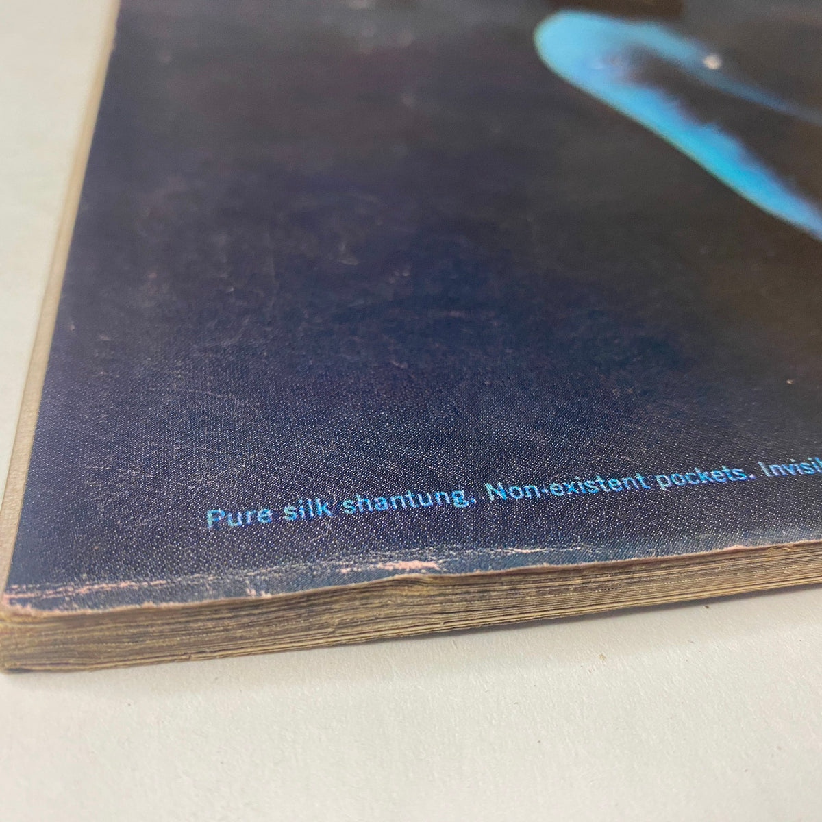 Close-up of the Vogue Magazine April 15, 1961 showing detail of the spine with text 'Pure silk shantung. Non-existent pockets. Invisible zippers.', highlighting vintage fashion details.