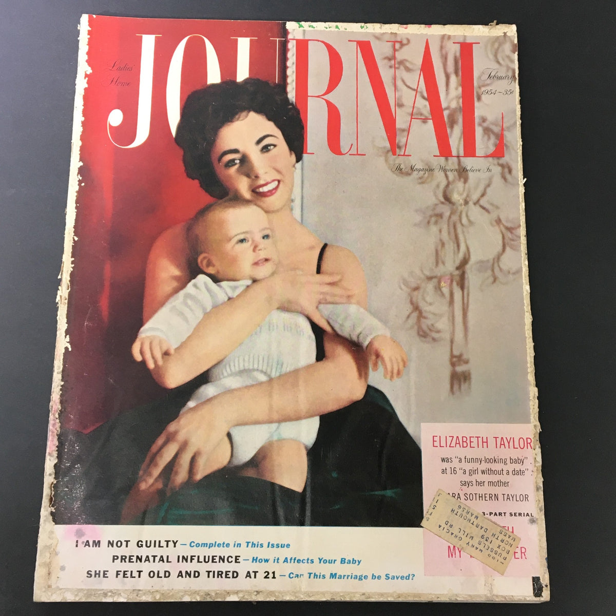 Cover of the VTG Journal Magazine February 1954 featuring Elizabeth Taylor holding her baby with a red and white design and magazine title clearly visible.
