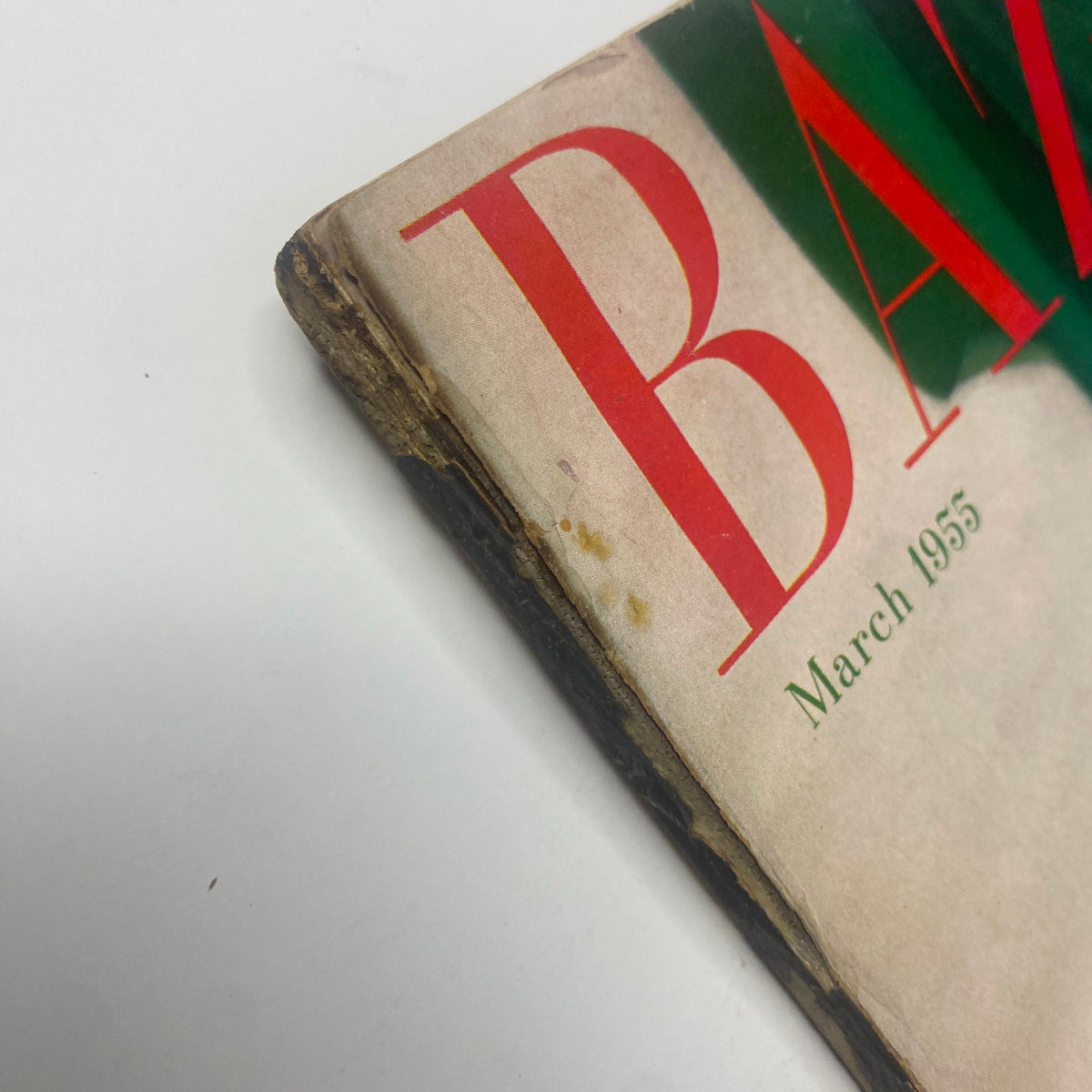 Side view of Harper's Bazaar Magazine March 1955 cover, showcasing wear with frayed edges and light discoloration.