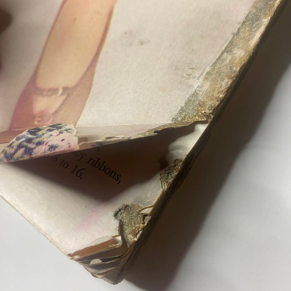 Detail view of the spine of Harper's Bazaar Magazine March 1955, revealing torn edges and wear indicating its vintage condition.